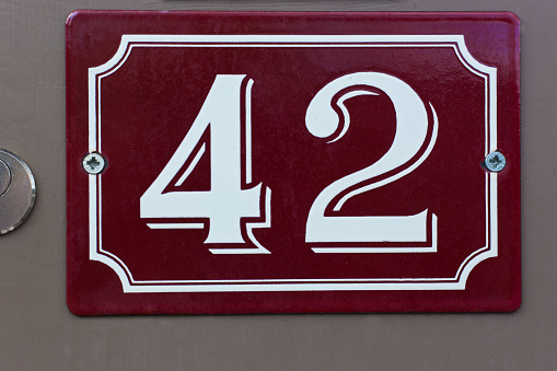 Weathered grunge square metal enameled plate of number of street address with number 29 closeup