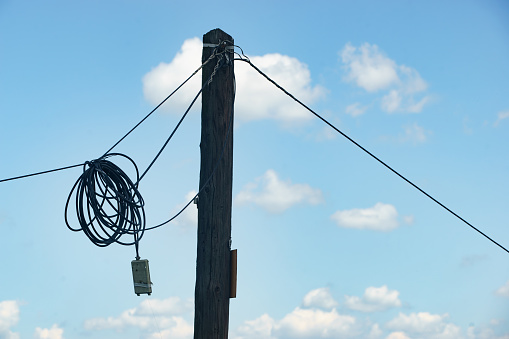 Tunari, Romania - Mai 24, 2023: Cables hang on an old wooden pole.