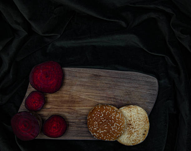 Burger on wooden board. On dark brown cloth.