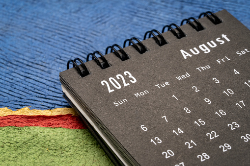 August 2023 - closeup of a small desktop calendar against abstract paper landscape, time and business concept