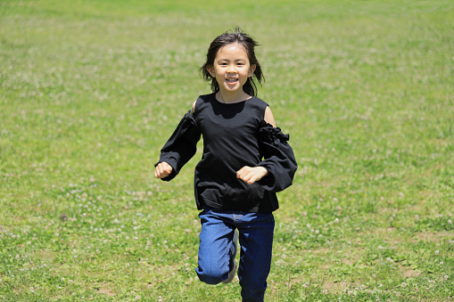 Japanese student girl running on the grass (8 years old)