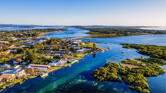 Lake Macquarie is Australia's largest coastal seawater lake and a perfect gateway. The beautiful lake is ideal for water sports and holiday staying and sits next to stunning ocean beaches. This is a drone picture with the outlook of houses, buildings and bridges showing the lively lifestyle living around this lake.