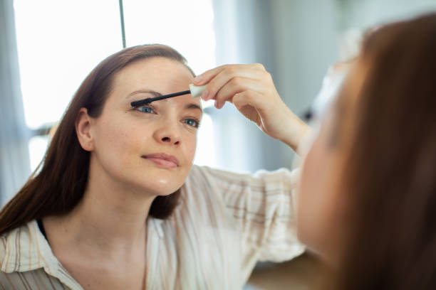 istock Young woman putting on makeup while looking in a mirror at home 1493864429