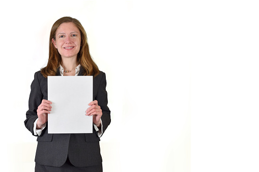 Business woman in charcoal suit holding an 8.5x11 flyer. Woman is isolated on white background and image contains clipping path around the sign/flyer to make it easy to add your design.