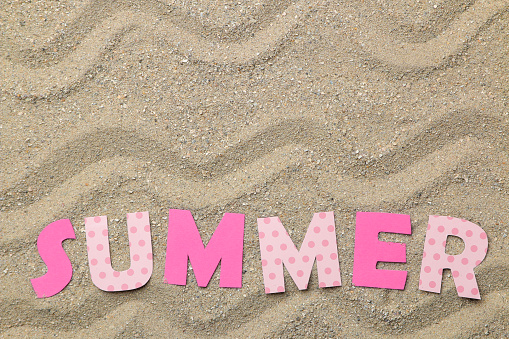 Lettering summer of paper pink letters on sea sand. Summer. relaxation. vacation. top view