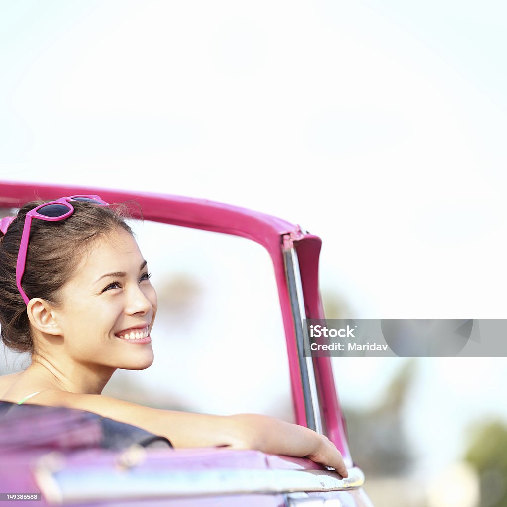 Car woman Car woman smiling happy enjoying car road trip travel vacation. Young retro woman in pink vintage convertible car looking to side at copy space. Beautiful young multiracial caucasian / chinese asian female model. Photo from Havana, Cuba. Car Stock Photo