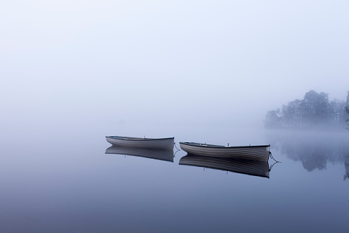 Two boats, shrouded in mist at dawn on Loch Rusky.