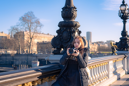 Pensive young Latin woman traveler looking away during sightseeing trip in Paris, France