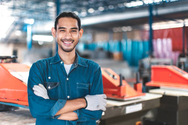 istock Factory asian man Worker using  and working industry engineers partner looking at camera and smile in factory.Engineer man wearing safety helmet working and checking machine. 1493899358