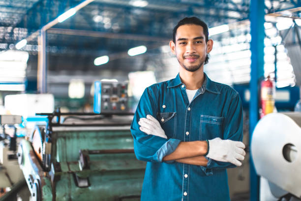 istock Factory asian man Worker using  and working industry engineers partner looking at camera and smile in factory.Engineer man wearing safety helmet working and checking machine. 1493899380