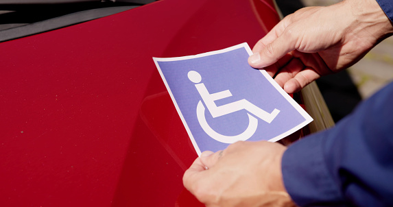 Driver Putting Wheelchair Sticker Sign On Car Vehicle
