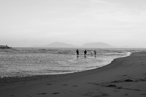 Amazing silvery light surrounds a family enjoying a beautiful beach in New South Wales, Australia.  Note the people are in silhouette and not recognizable.