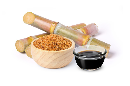 Brown unrefined cane sugar in wooden bowl and sugar syrup with fresh sugar cane isolated on white background.