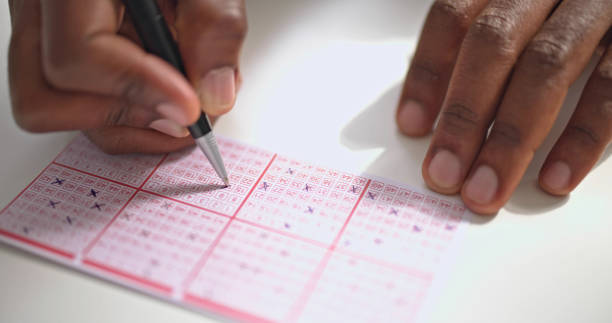 istock Person's Hand Marking Number On Lottery Ticket 1493924701