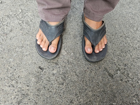 Asian male feet wearing sandals outdoors.  stock photos