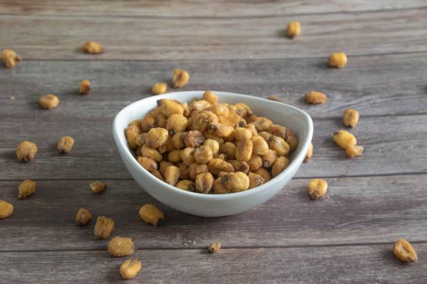 istock peanuts in a bowl on a wooden table with other peanuts scattered around it 1493935322