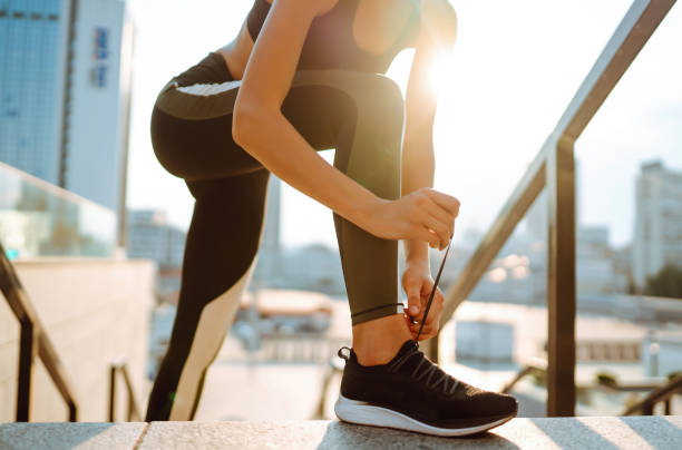 istock Young woman getting ready for jogging outdoors while lacing her sneakers 1493935636