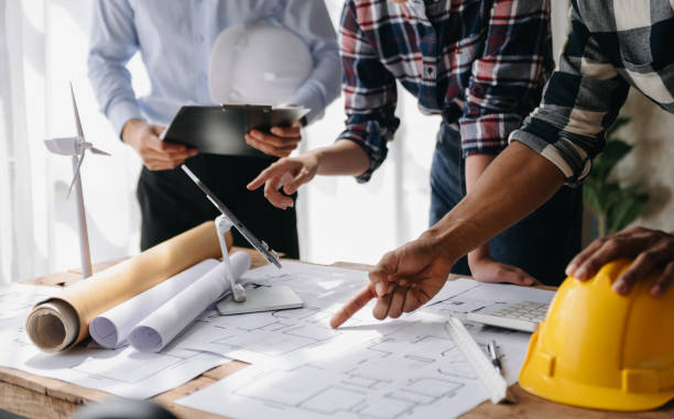 istock Engineer teams meeting working together wear worker helmets hardhat on construction site in modern city. industry professional team in office 1493936842