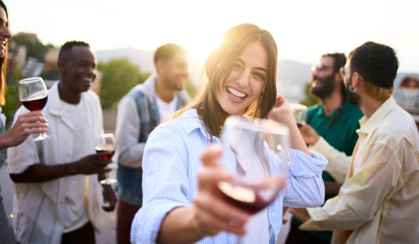 Portrait of pretty young woman looking at camera with glass of red wine in hand and smiling. stock photo