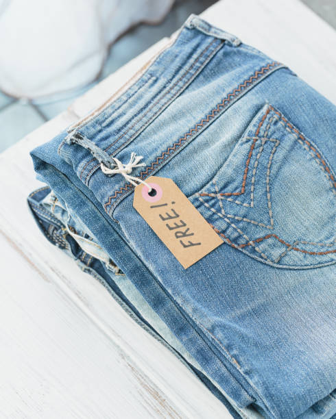istock Stack of blue jeans and tag with inscription free on white background 1493938843