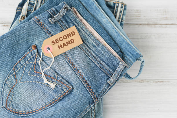 istock Stack of blue jeans and tag with inscription second hand on white background 1493938852