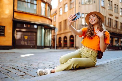 Young woman olding mobile phone taking selfie photo using smartphone camera.