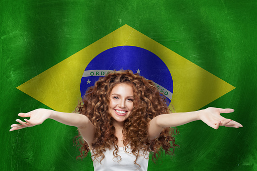 Welcome to Brazil. Happy woman with red suitcase on Brazilian flag background. Travel, work, education and internship in Brazil concept