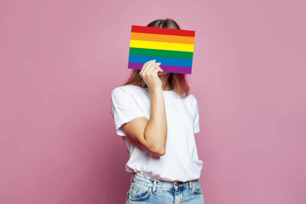 istock Anonymous woman covering face with LGBT sing on pink background 1493946465