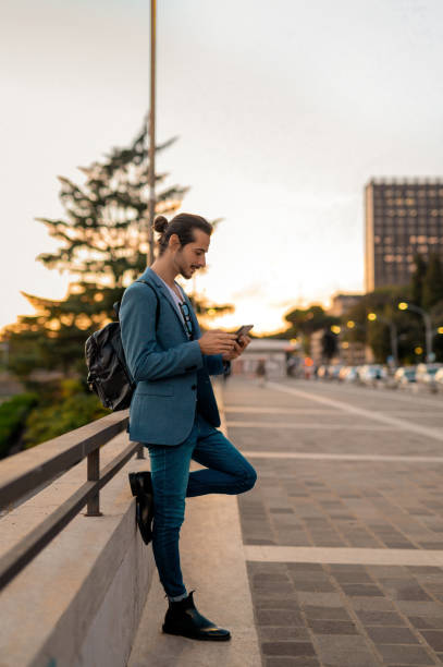 istock Side view of smart casual businessman using cellphone on sidewalk 1493959267