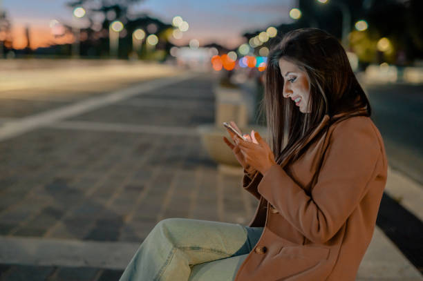 istock Side view of businesswoman on bench, using cellphone at dusk 1493959325