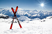 Pair of red skis crossed and wedged in snow on mountain