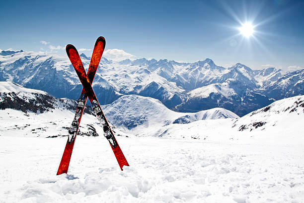 Pair of red skis crossed and wedged in snow on mountain Pair of cross skis in snow snow mountain range european alps mountain peak stock pictures, royalty-free photos & images