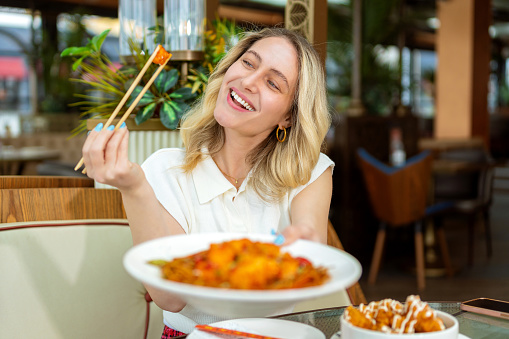 Hungry woman with plates of dinner in restaurant