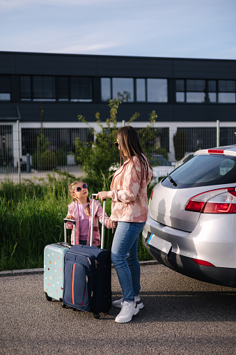 Mom and daughter stand near the car with their suitcases and waiting for the trip. Family journey . High quality photo