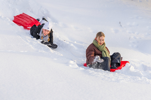 Young girls playing in the snow with sleds in Lapland, Finland