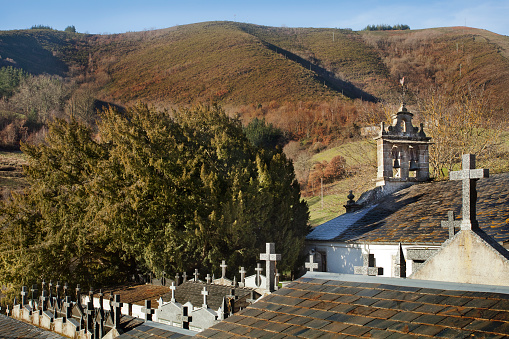 Córneas village church , cemetery, ancient large yew tree, mountainous landscape in the background  . Baleira, Lugo province, Galicia, Spain.