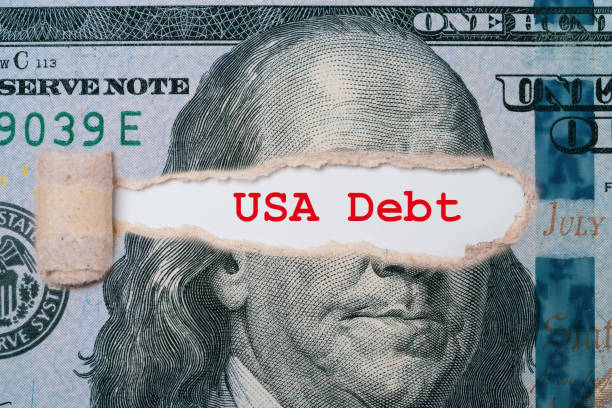 istock Benjamin Franklin face from USD dollar banknote behind of torn paper with debt wording for America's public debt is high and the debt ceiling needs to be raised concept. 1493969248