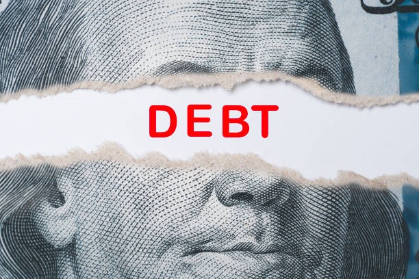 istock Benjamin Franklin face from USD dollar banknote behind of torn paper with debt wording for America's public debt is high and the debt ceiling needs to be raised concept. 1493969293