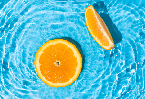 istock Fresh round orange slices floating in a pool with a rippled saturated blue water. Minimal tropical fruit creative art. Summer refreshment concept. 1493971162