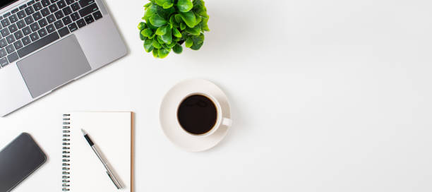 istock Laptop and coffee cup on a white table in the office. Working concept using technology, smartphones, notebook, internet. Copy space on right for design or text, Close up, top view white background 1493972134