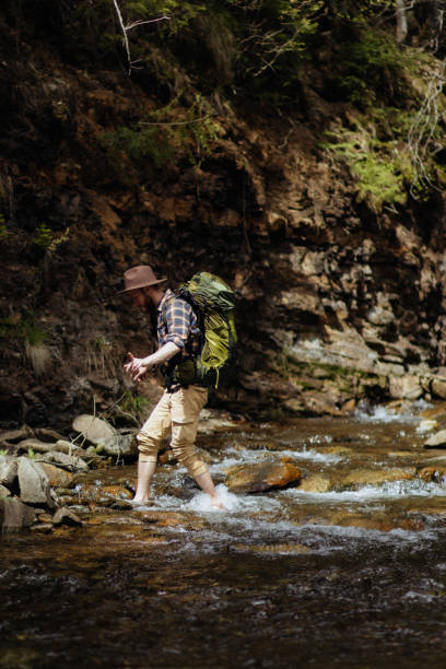 istock The man with a backpack crosses the mountains stream during the hiking 1493980340