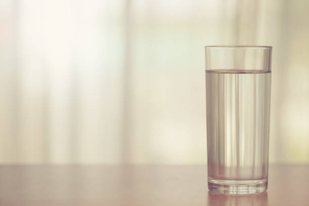 istock Glass of drinking water on blurred white curtain background 1493982996