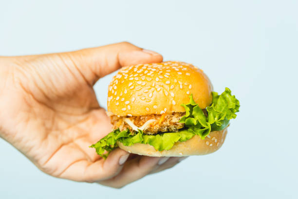 istock Hand holding a delicious hamburger on blue background 1493982998