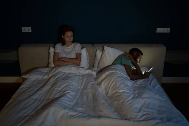 istock Indifferent man husband using smartphone, ignoring sad unhappy wife while lying together in bed 1493987920