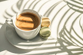 Coffee and cakes on the table with plant shadows