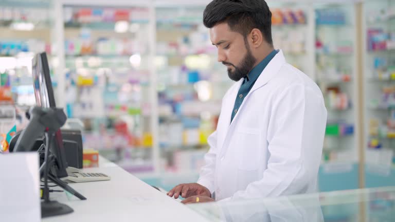 4K Indian man pharmacist working at modern pharmacy