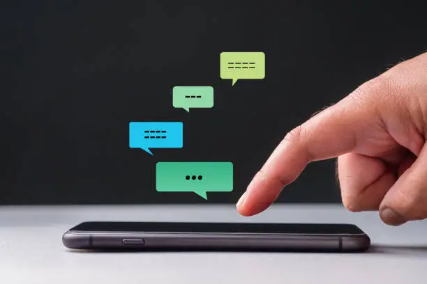 Closeup index finger is going to touch the screen of a smartphone to type the chat message