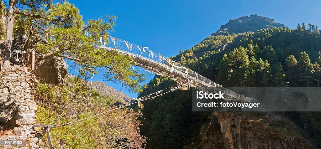 ワイヤのつり橋カラフルな祈祷旗を峡谷ヒマラヤ山脈ネパール - ロープのつり橋のロイヤリティフリーストックフォト