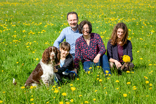 Happy family with dog sitting in a meadow