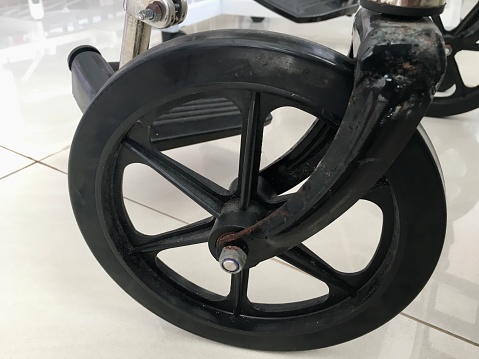Photo of a black wheelchair wheel on a white floor